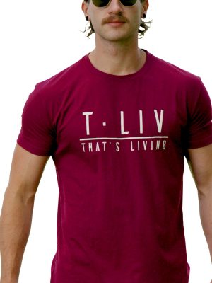 A man with slicked-back hair, a mustache, and sunglasses wears the Genesis Tee - Maroon featuring "T-LIV THAT'S LIVING" on the front, standing against a white background.