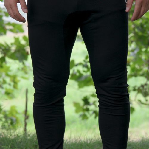 A person is outdoors wearing Genesis Joggers - Black and white sneakers, with green foliage and grass in the background. Only the lower torso and legs are visible.