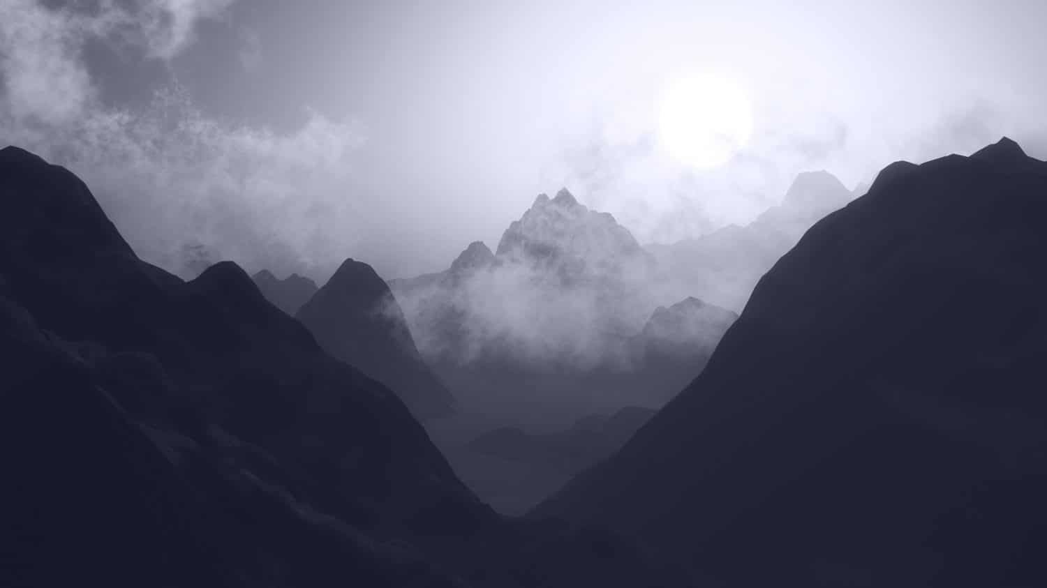 A grayscale image of a mountainous landscape at sunrise or sunset, with the sun shining through mist and clouds, silhouetting the jagged peaks and creating a dramatic, serene atmosphere.