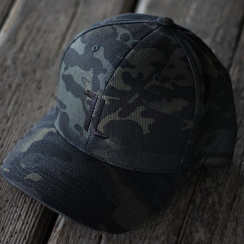 The Original Ball Cap - MultiCam features a subtle embroidered logo on the front and is shown resting on a weathered wooden surface.