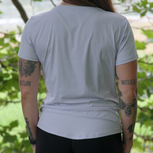 A person wearing the VeloraFlow Tee - Whisper Blue, displaying arm tattoos.