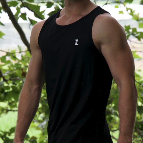 A man in sunglasses wears the Genesis Tank V2 - Black with the TL logo, standing outdoors among green trees and looking confidently at the camera.