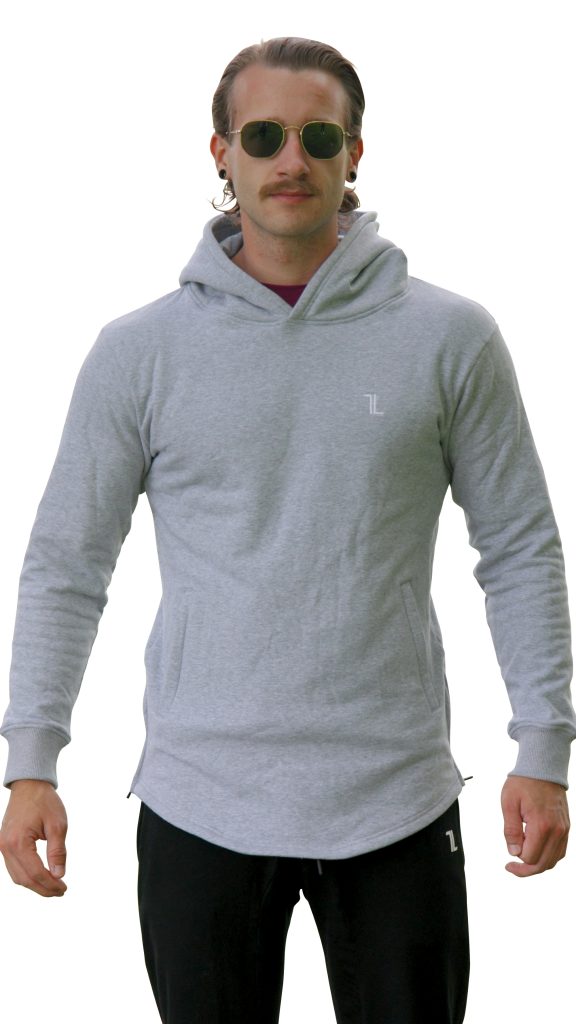 A man with long hair tied back wears the SPEKTR Hoodie - InfraGrey, featuring a small white logo, paired with black pants with a white logo. He faces forward and completes the look with sunglasses.
