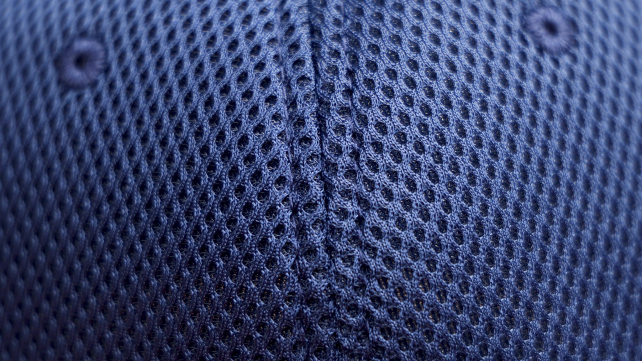 Close-up of navy fabric from the Mesh Ball Cap - Navy, featuring a breathable mesh design, flex fit, and a stitched seam running vertically down the center.