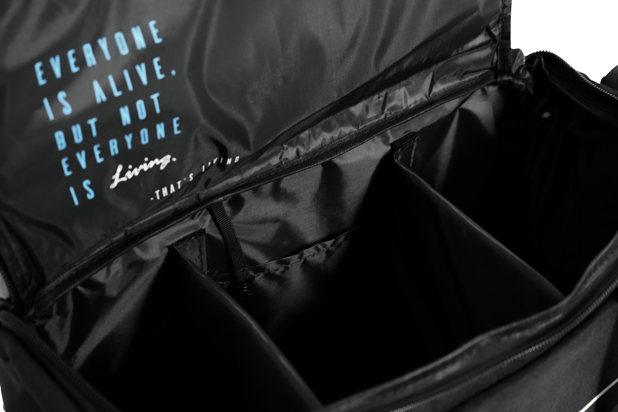 The TRIARC Duffle Bag features an organized black interior with dividers and a quote on the inner flap: "Everyone is alive, but not everyone is living. — That’s a fact" in blue and white text.