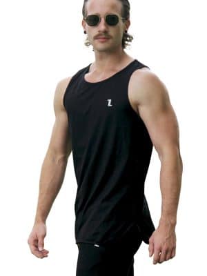 A man with slicked-back hair and sunglasses stands slightly angled in a black Genesis Tank V2 and black pants against a white background.
