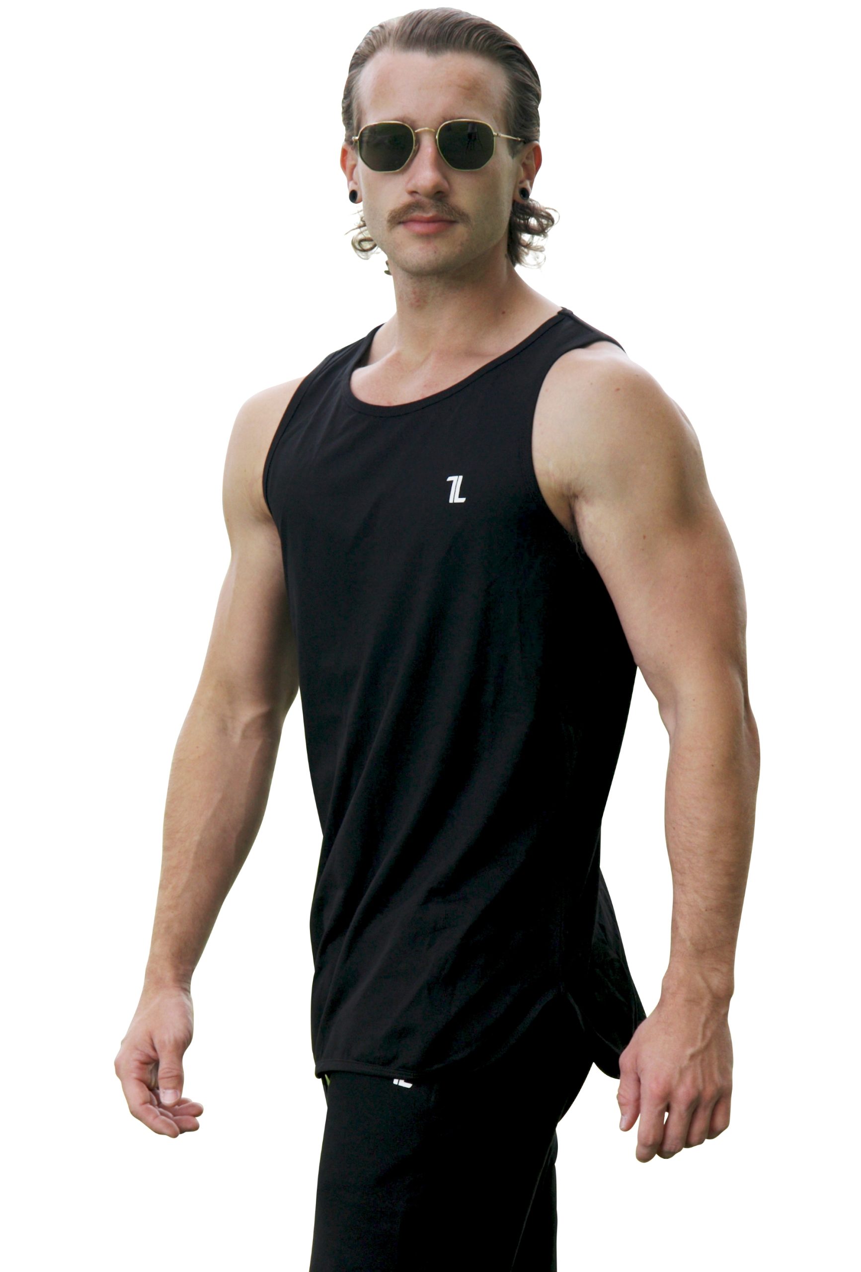 A man with slicked-back hair and sunglasses stands slightly angled in a black Genesis Tank V2 and black pants against a white background.