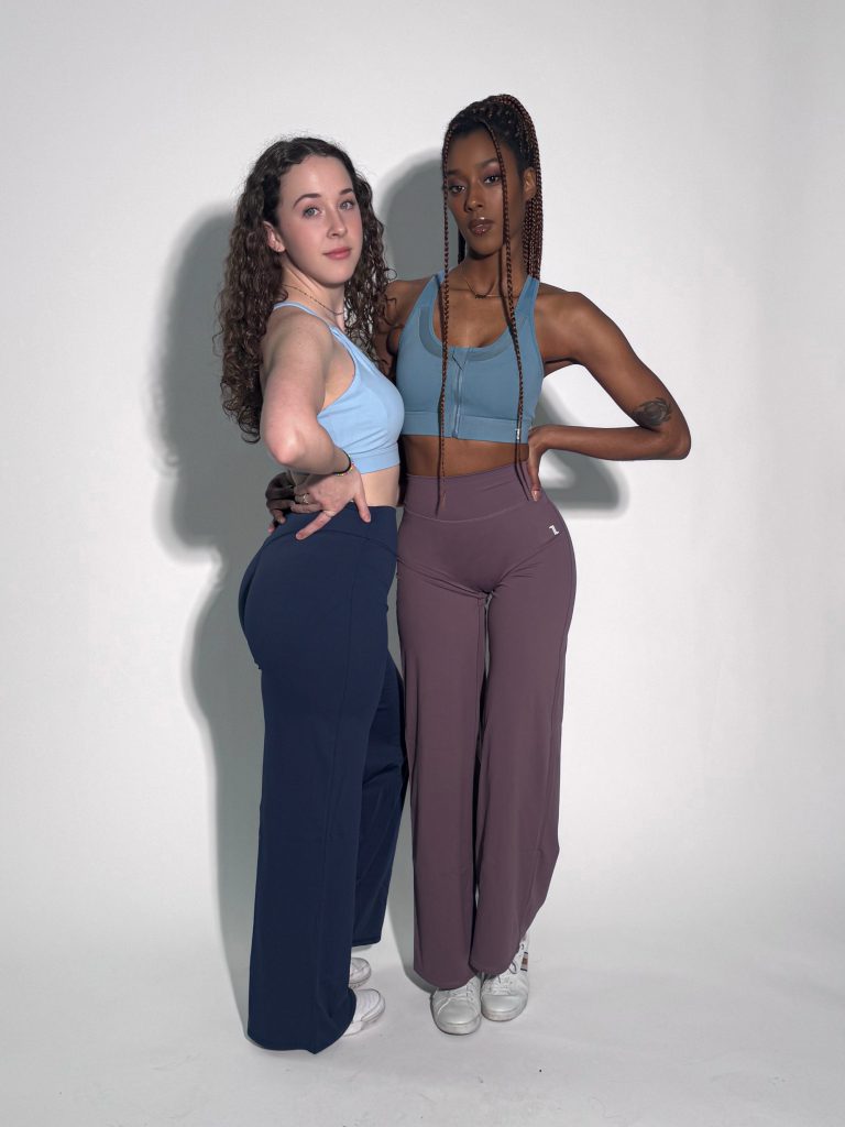 Two women pose in sleeveless crop tops and Sculpted Straight Flare Legging sets—one dark blue, one mauve—against a light background, showcasing the form-flattering and squat-proof sculpting activewear.