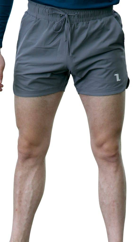 A person wearing gray athletic shorts with a small white logo on the left leg, standing with legs slightly apart against a white background.