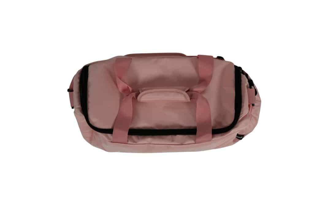 The TRIARC Duffle Bag features a light pink color with matching handles, a black zipper, and a small side pocket, displayed against a white background.