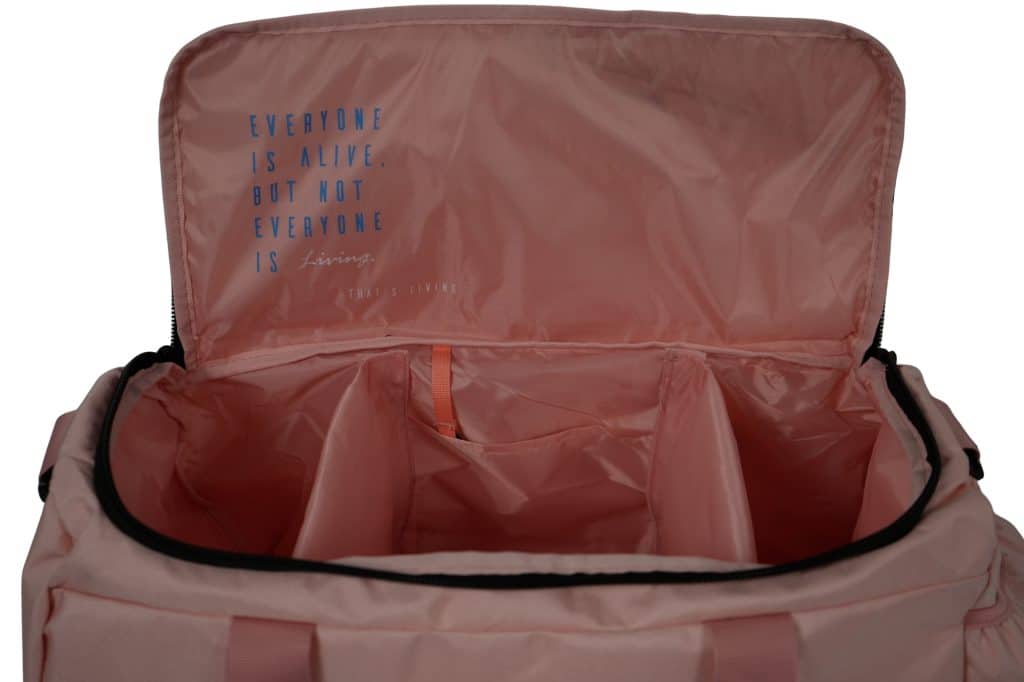 Open TRIARC Duffle Bag in pink with compartments, revealing the inner lid inscription: "EVERYONE IS ALIVE, BUT NOT EVERYONE IS Living. (THAT'S LIVING)," in blue and white text.