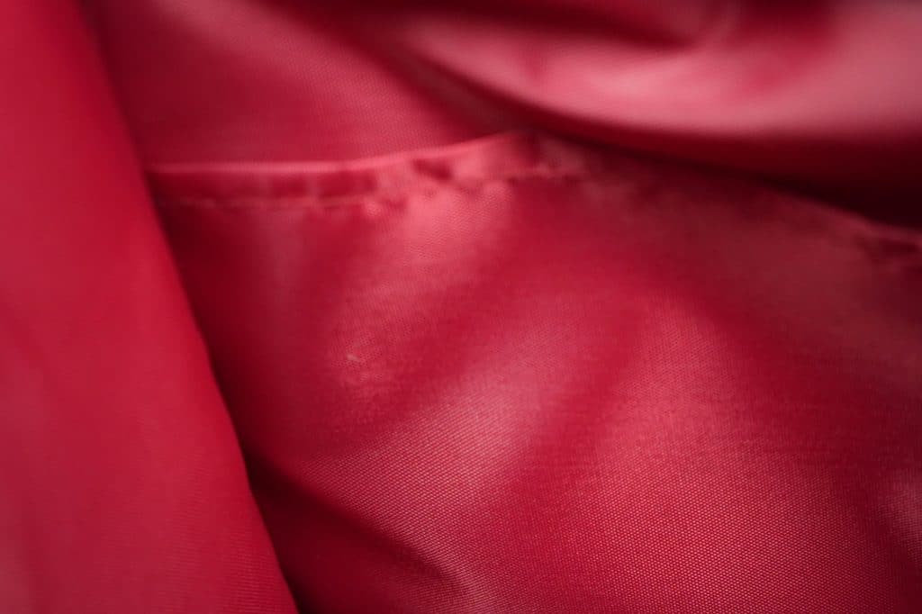 Close-up of the smooth, shiny red interior lining with visible stitching and soft folds inside the TRIARC Duffle Bag.