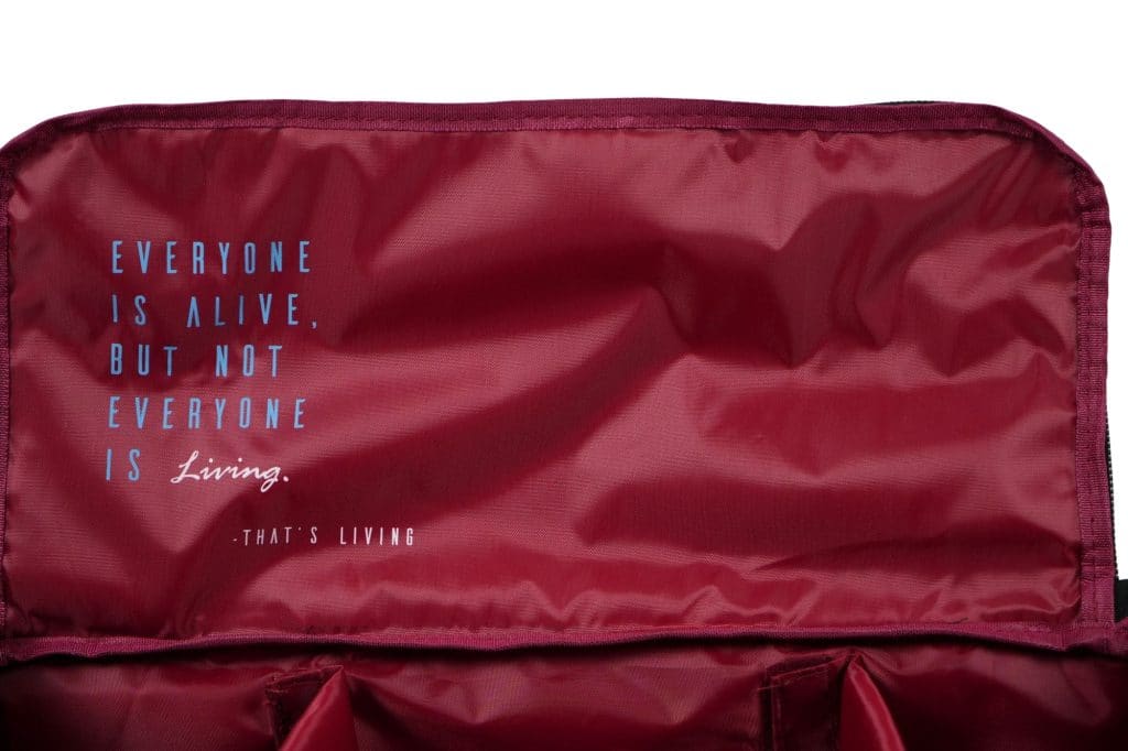 Maroon fabric inner lining with the quote: "EVERYONE IS ALIVE, BUT NOT EVERYONE IS Living. -THAT'S LIVING" printed in blue and white text.