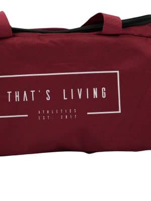 A red duffel bag with “THAT'S LIVING” and “ATHLETICS EST. 2017” printed in white on the side. The bag has short handles and a zipper on top.