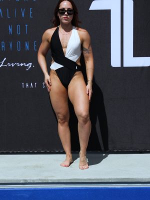 A woman wearing a black and white swimsuit and sunglasses stands poolside in front of a dark backdrop with white and blue text.