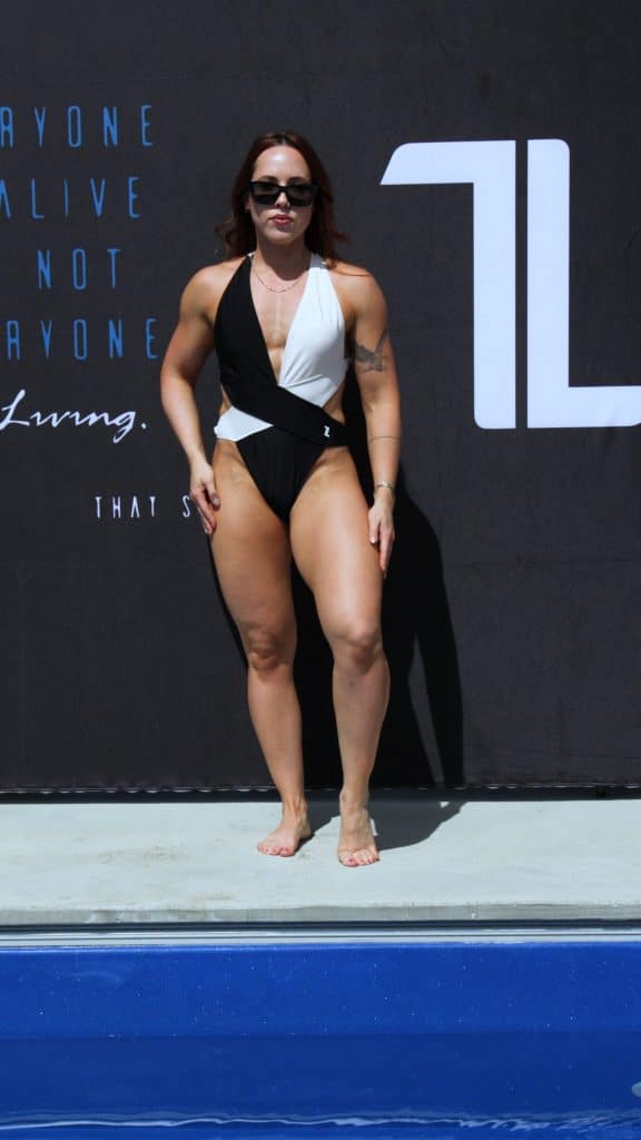 A woman wearing a black and white swimsuit and sunglasses stands poolside in front of a dark backdrop with white and blue text.